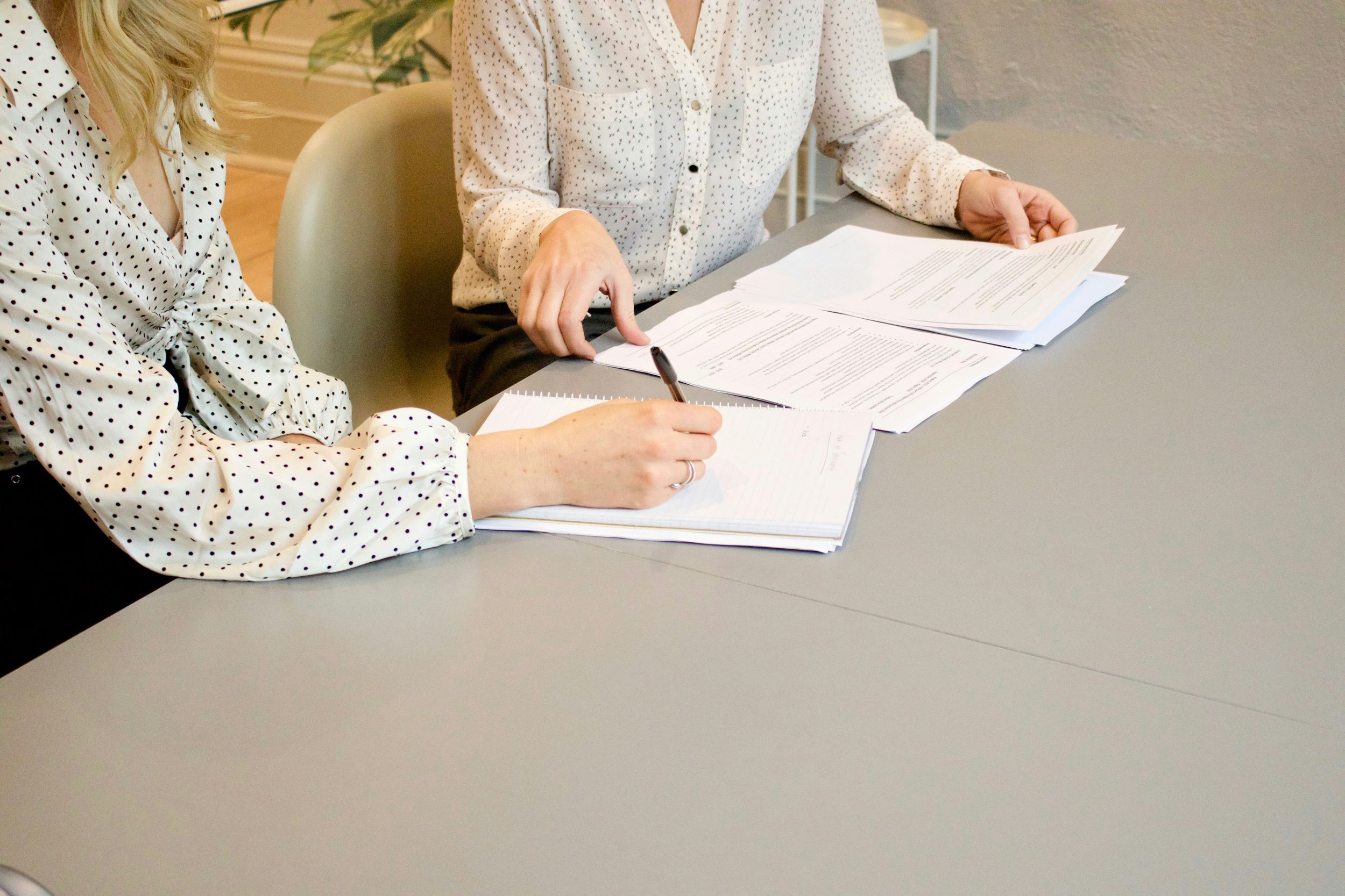 Two women signing a document. The documents could be an Apostille, Affidavits, or Certified True Copies